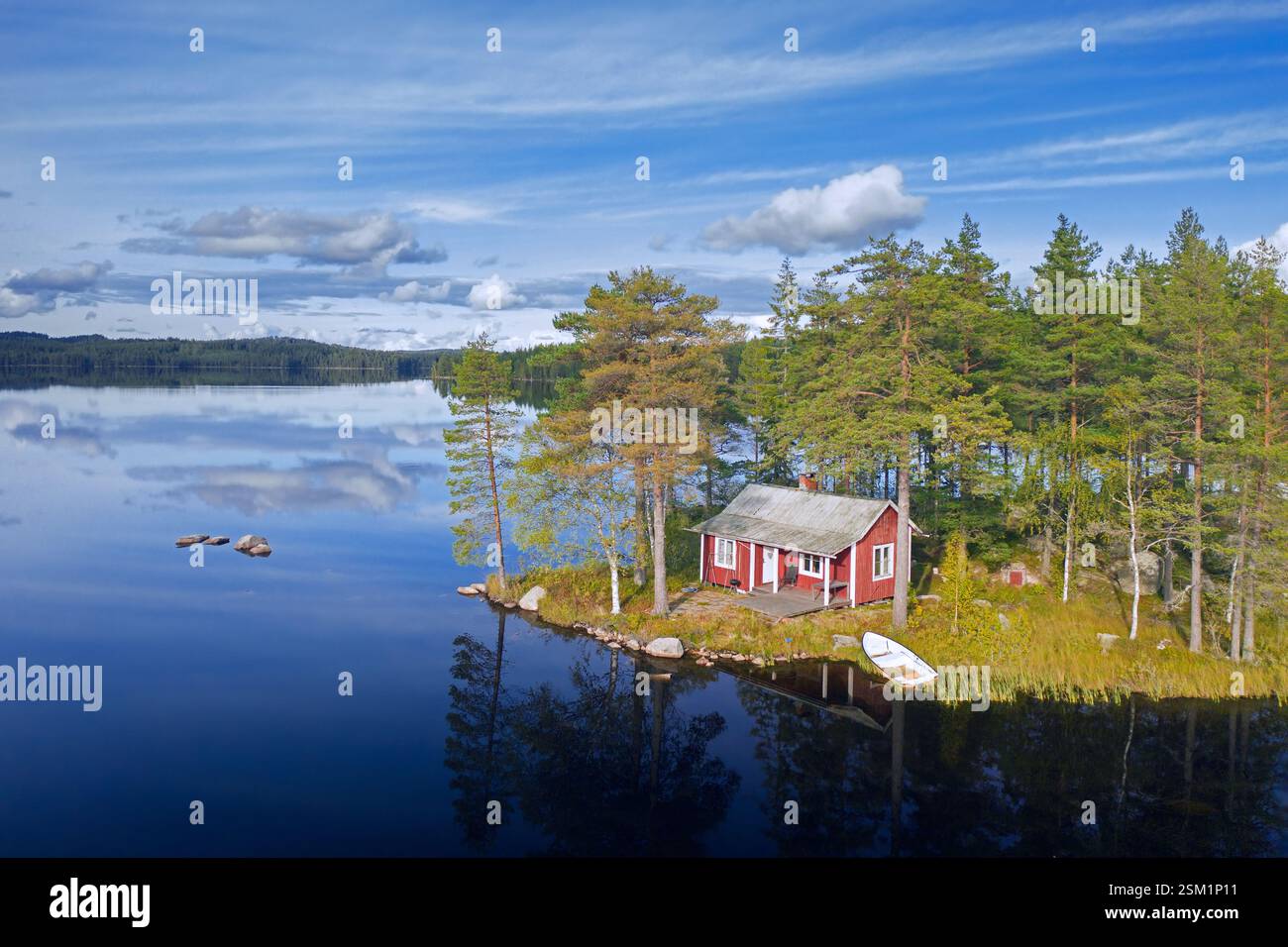 Piccola e solitaria cabina tradizionale in legno rosso lungo la riva del lago in autunno/autunno, Värmland, Svezia centro-occidentale, Scandinavia Foto Stock