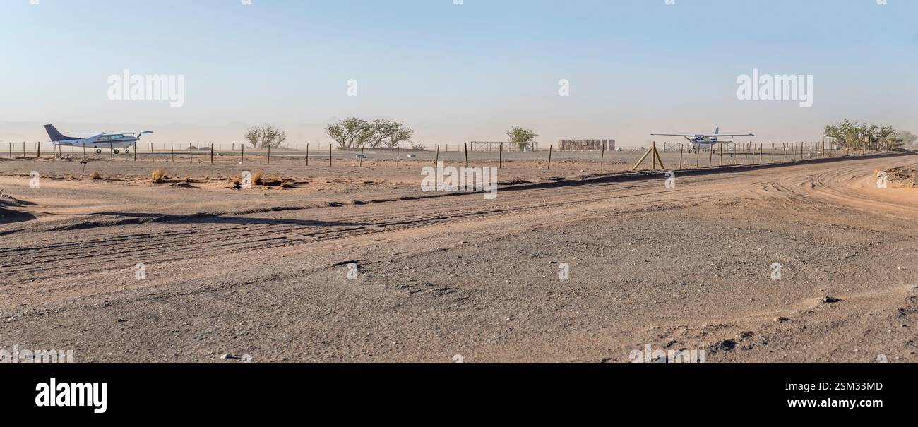 Paesaggio con piccoli aeroplani parcheggiati sul grembiule nella pista di atterraggio nella campagna desertica, girato con la luce brillante della tarda primavera vicino a Twyfelfontein, Namibia, Afric Foto Stock