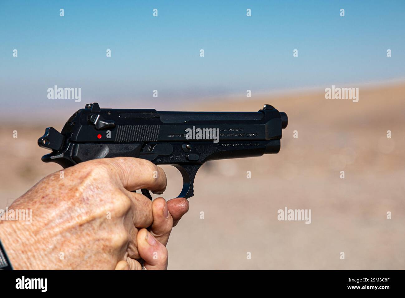 Un uomo spara a una pistola semi-automatica nera durante la pratica del bersaglio. La pistola puntava a destra. Foto Stock