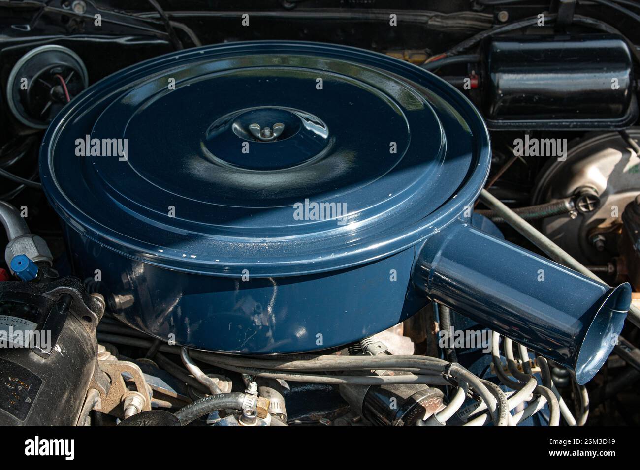 Un vecchio alloggiamento del filtro dell'aria in metallo blu sopra un classico motore a benzina V8 con carburazione. Foto Stock