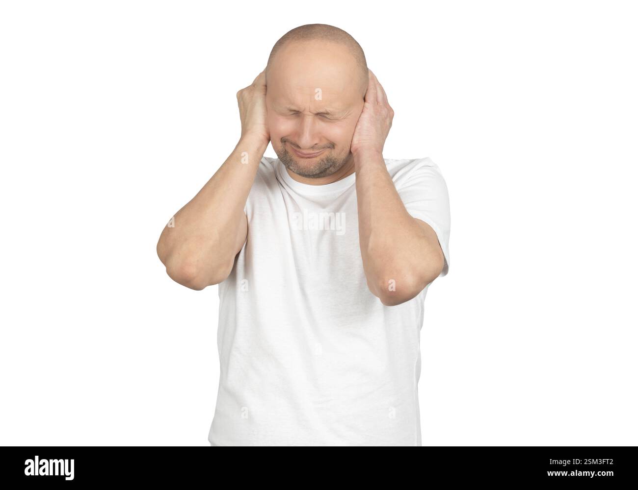 Un uomo caucasico calvo con stoppie leggere indossa una t-shirt bianca e copre le orecchie con entrambe le mani. Foto Stock