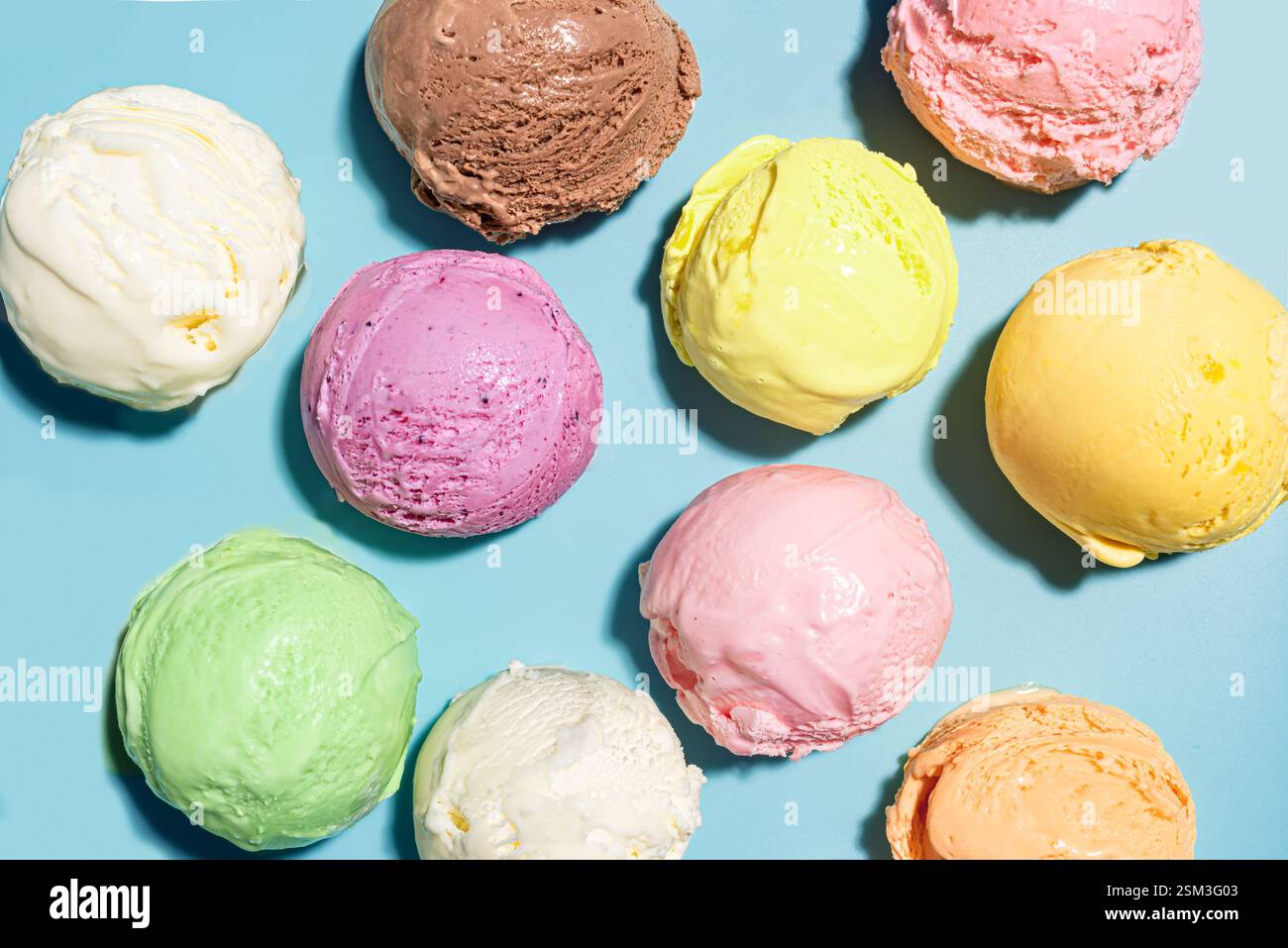 Palline di gelato assortite su sfondo blu, vista dall'alto, fantasia creativa. Vari gelati o gelati, sano concetto di dessert estivo. Foto Stock