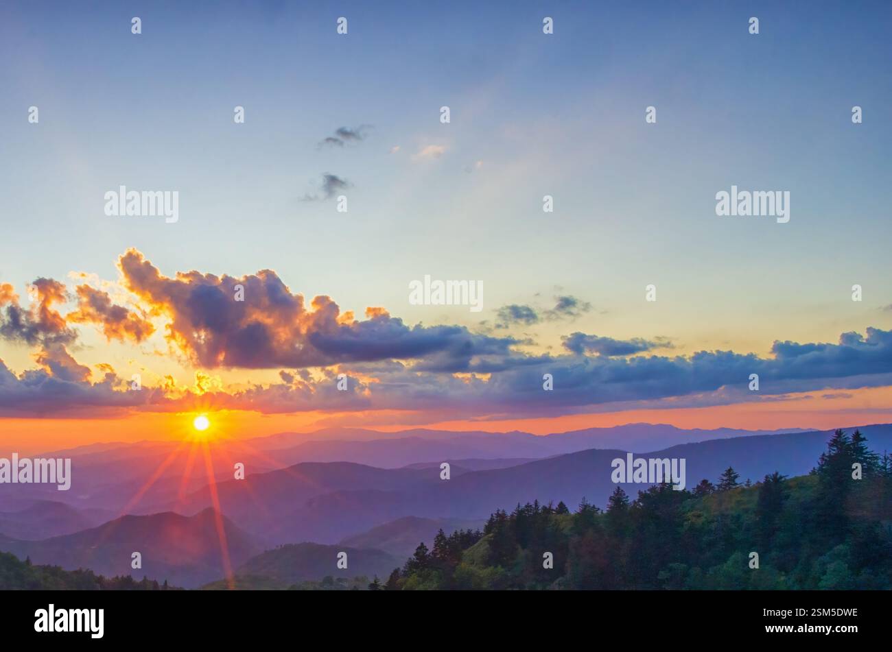 Una vibrante alba sulle Great Smoky Mountains, che getta luce dorata su colline ondulate e nuvole, creando un paesaggio mozzafiato e sereno. Foto Stock