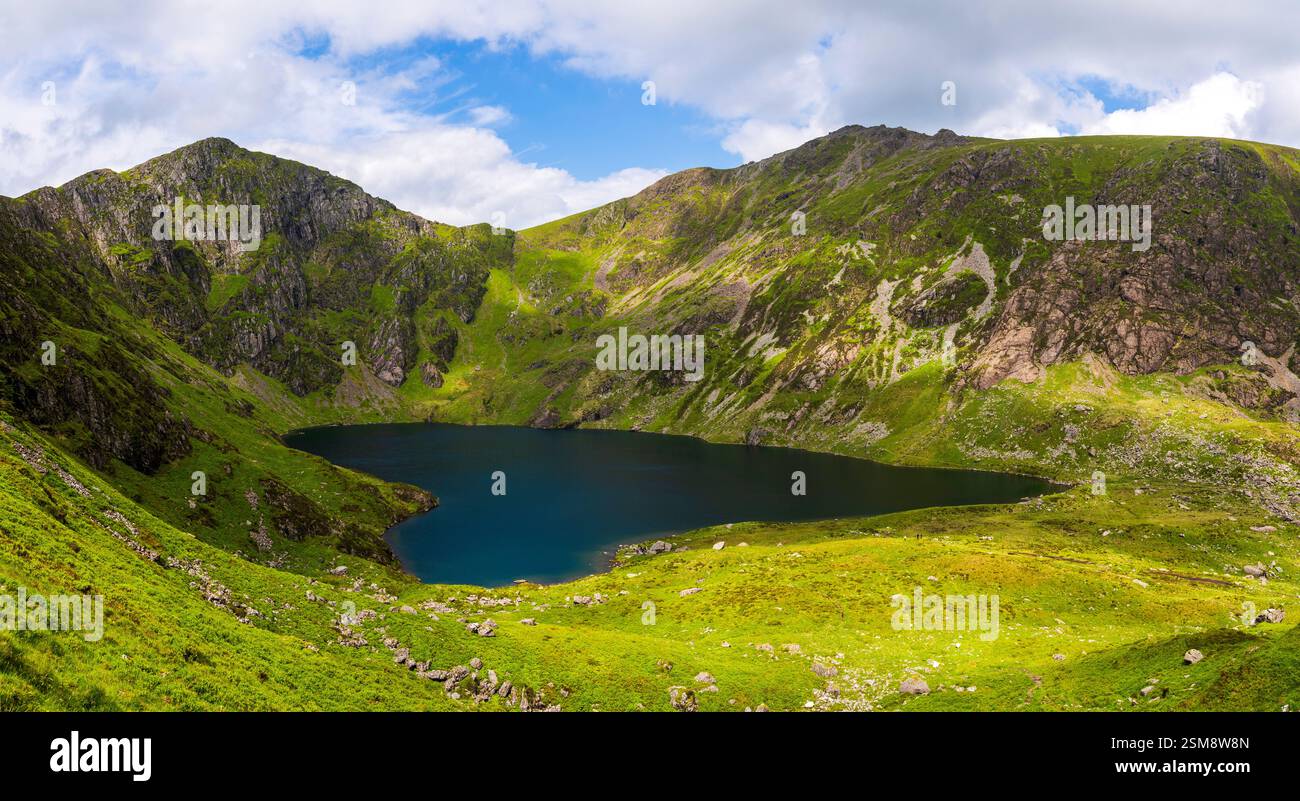 Pendii verdi vividi e picchi scoscesi di Penygader (Cadair Idris) che riflettono la bellezza Rugged di Llyn Cau nel Parco Nazionale di Snowdonia Foto Stock