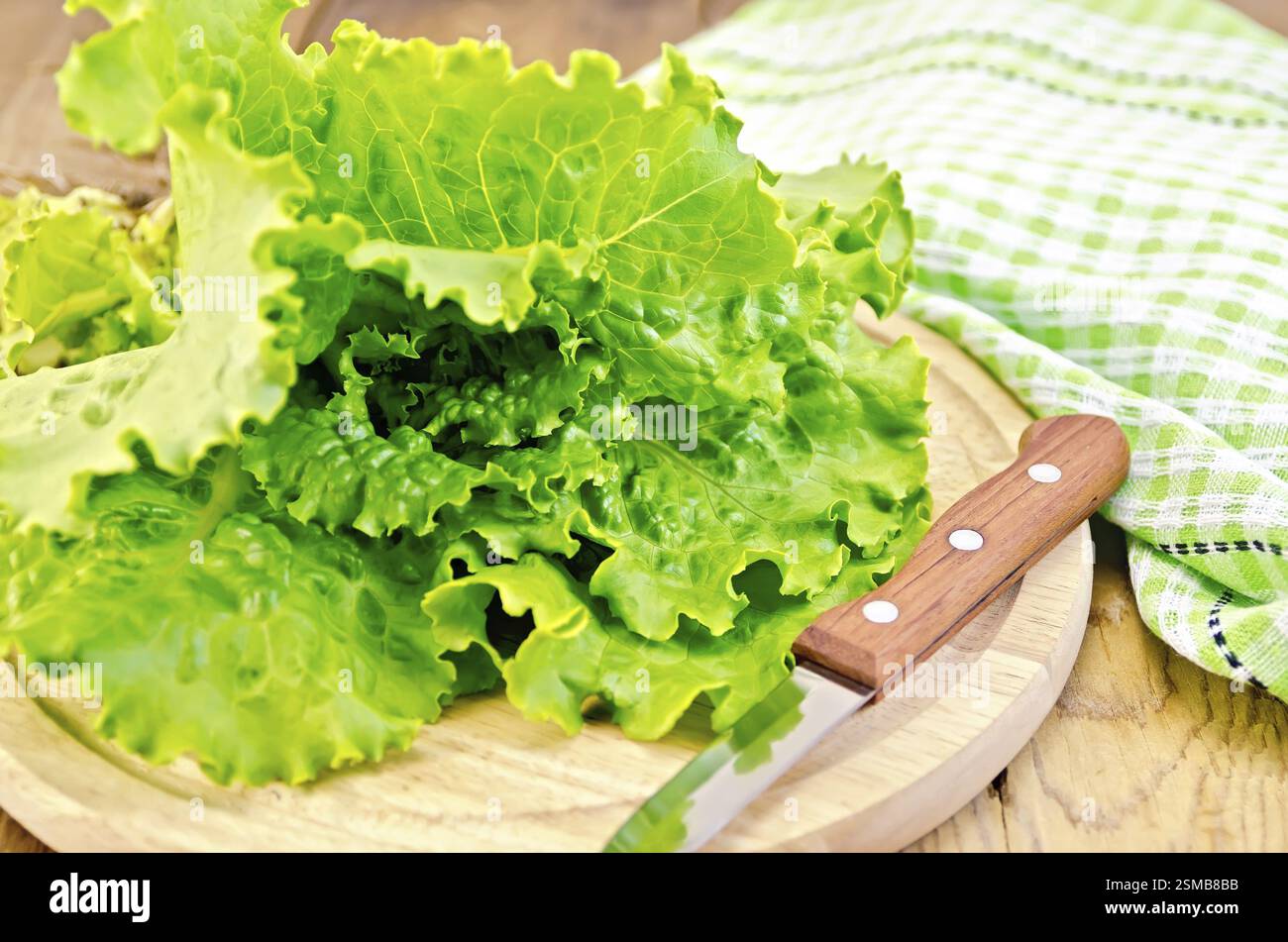 Insalata verde con la lama di un coltello, tovagliolo sulla tavola di legno Foto Stock