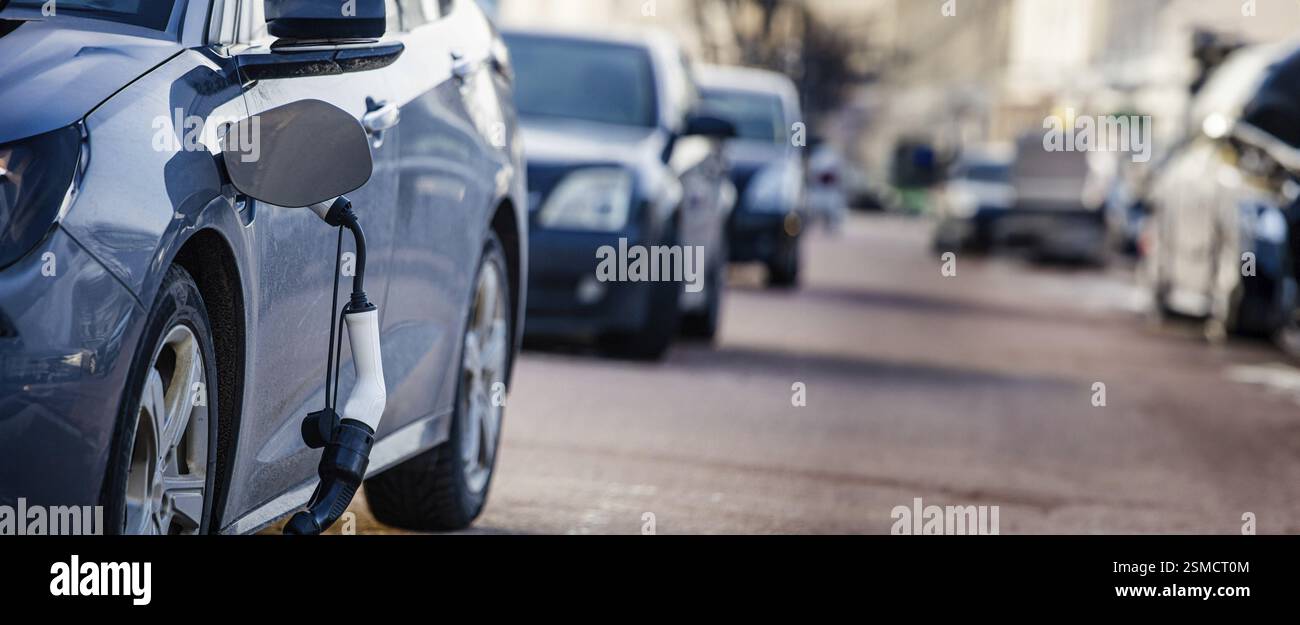 Diverse auto allineate su una strada della città con una sola ricarica per auto elettriche Foto Stock