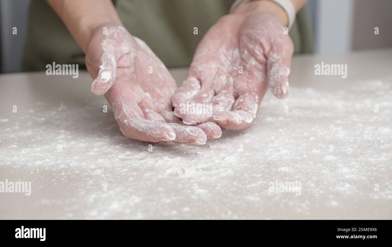 Mani, farina e cottura da donna in cucina per pane, pizza o cibo fatto a mano a casa. Cuoca di frumento, palme e donna con le dita disordinate della cucina, Foto Stock