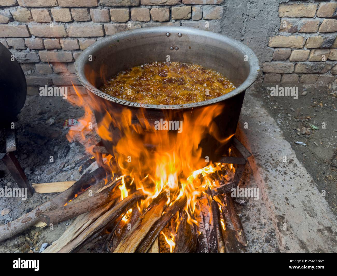 Grande recipiente di olio bollente sul fuoco aperto per cucinare all'aperto con un metodo tradizionale Foto Stock