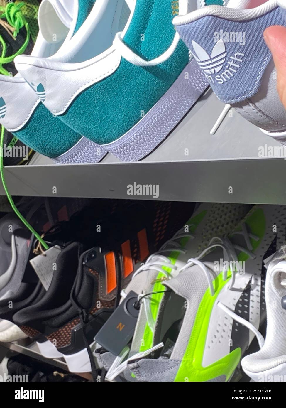 Primo piano di colorate sneakers Adidas disposte sugli scaffali espositivi, con vari stili e colori presso il centro commerciale outlet Fidenza Village Foto Stock