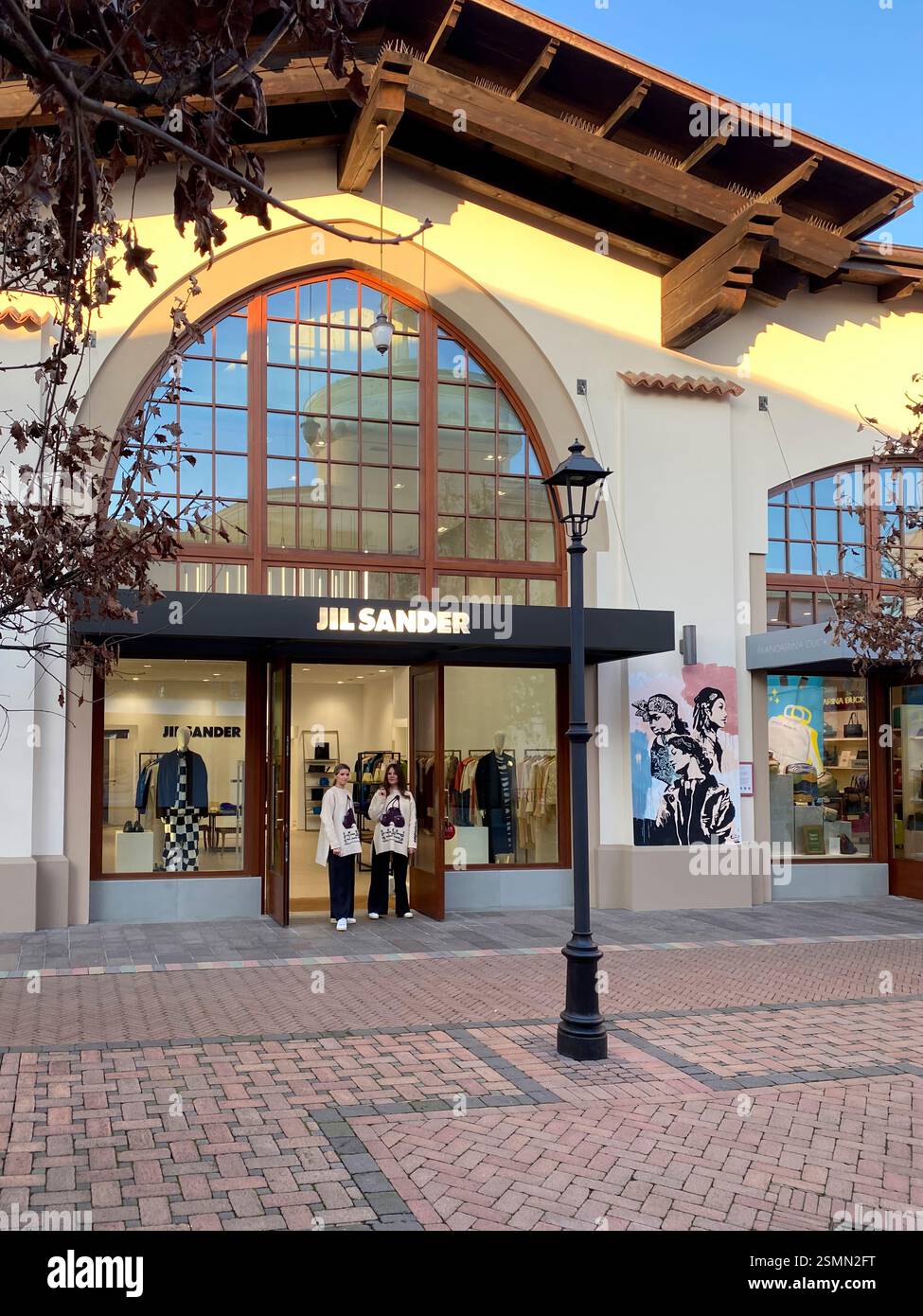 Gli amanti dello shopping si trovano di fronte al negozio Jil Sander di Fidenza Village, un centro commerciale outlet di lusso vicino a Milano Foto Stock