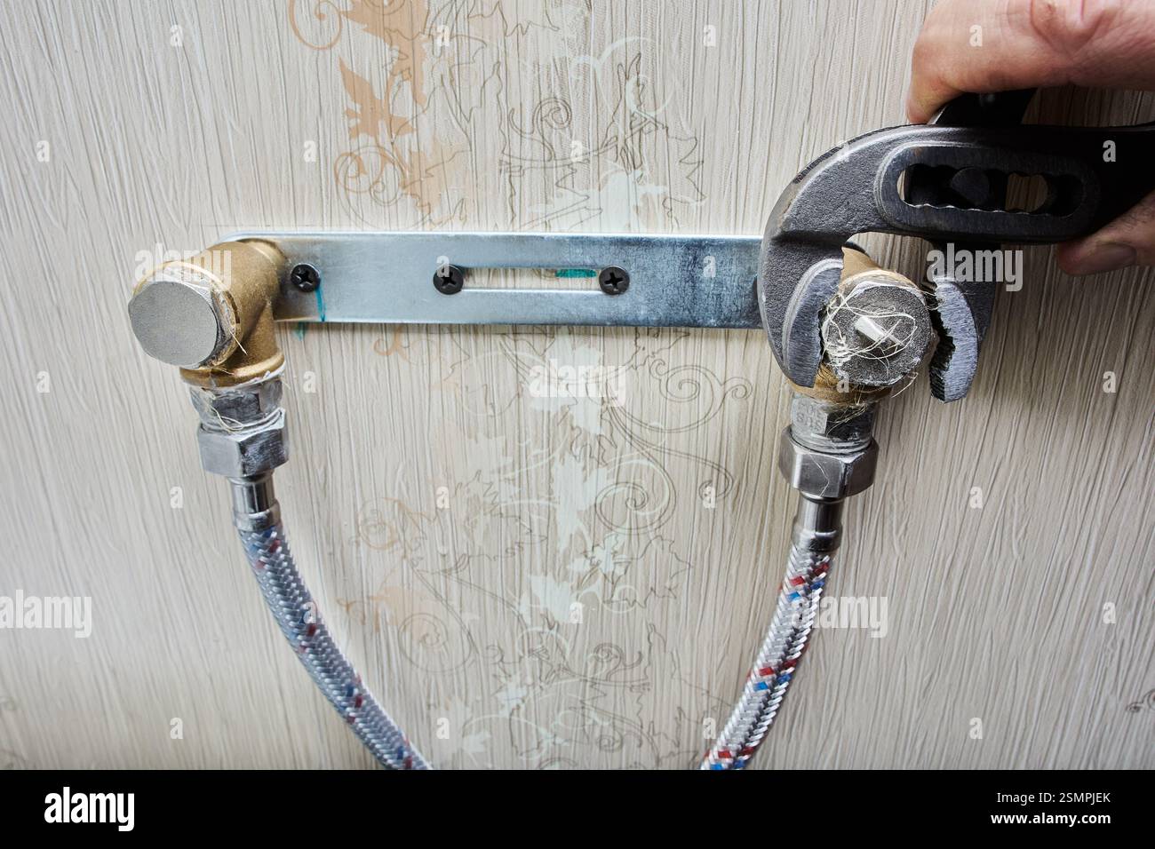 Il serraggio dei tappi per tubi con una chiave a pinza regolabile garantisce una tenuta sicura sulla staffa dell'impianto idraulico. Foto Stock