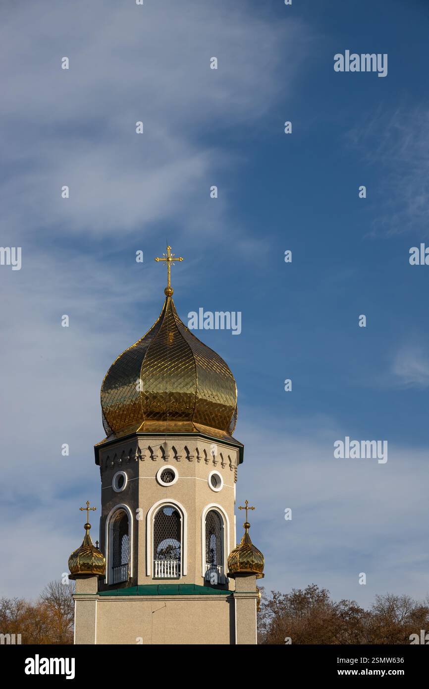 La cupola dorata di una chiesa risplende brillantemente sotto un cielo azzurro, mostrando intricate architetture e motivi incrociati in una giornata serena nei paesi Foto Stock