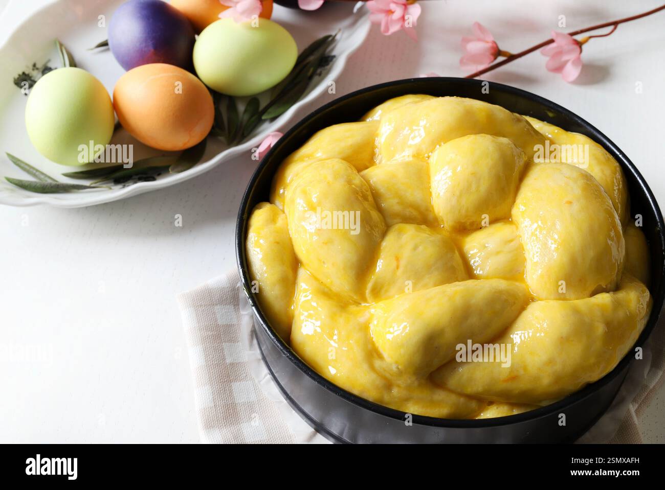 Pane dolce pasquale, cozonac o tsoureki sul tavolo e uova di Pasqua colorate su un legno bianco. Brioche intrecciate, dolce tradizionale natalizio. Foto Stock