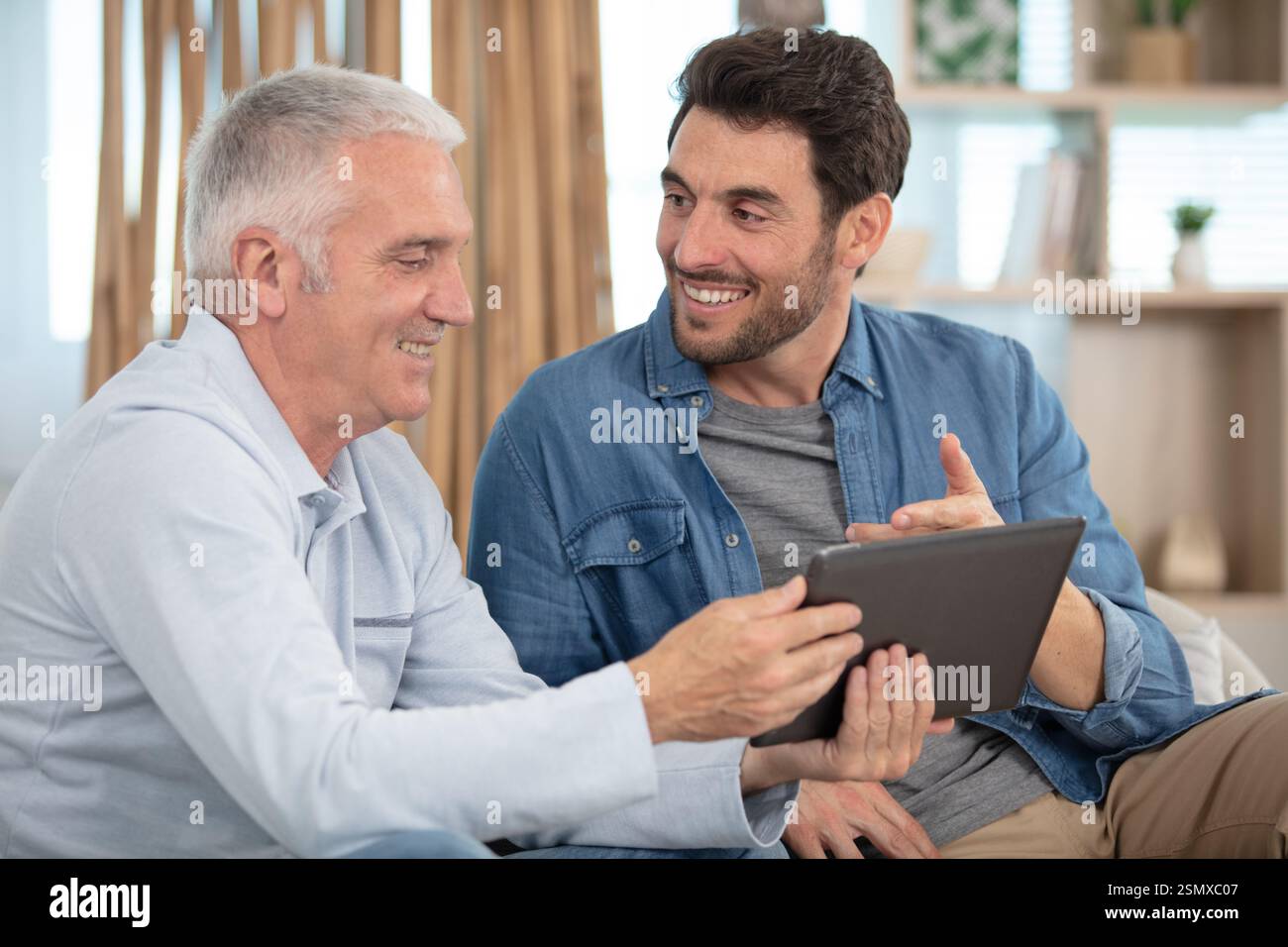 uomo anziano e uomo più giovane che controlla l'atablet Foto Stock