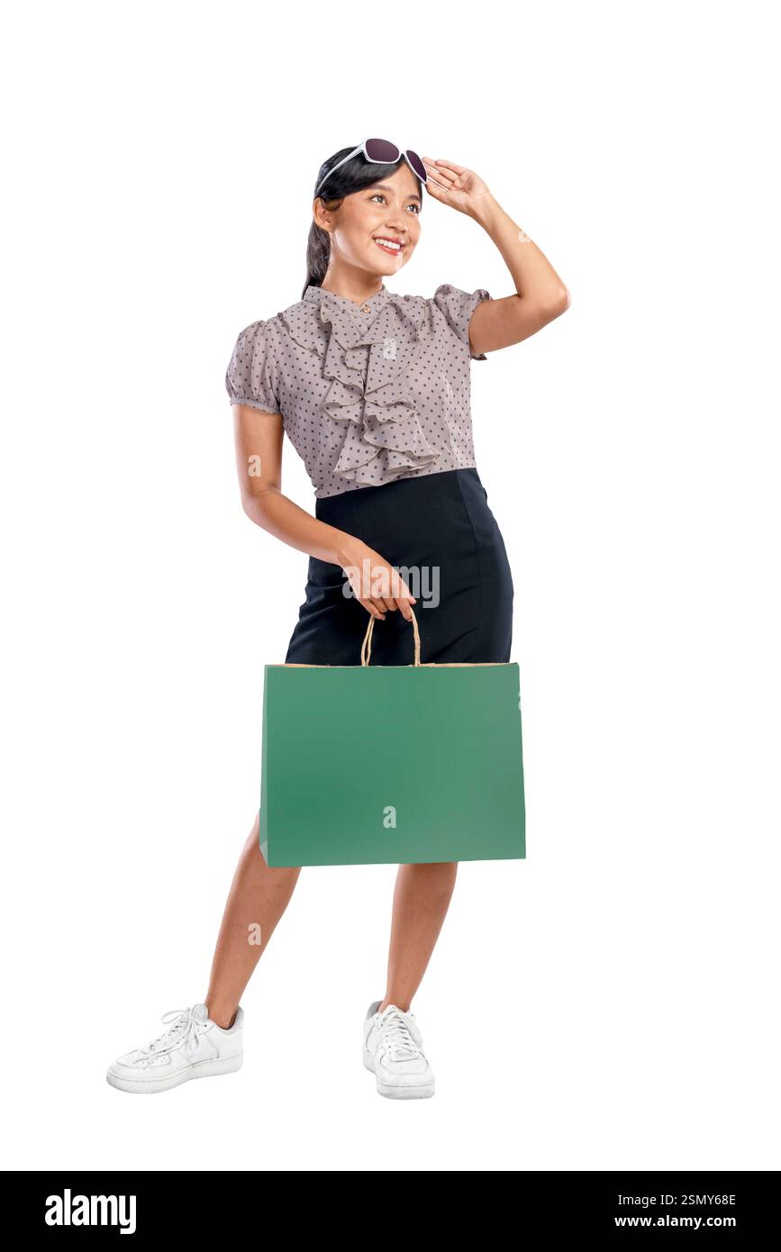 Ritratto di una donna asiatica indonesiana con occhiali da sole che portano una borsa della spesa isolata su uno sfondo bianco. Copia spazio o mockup. Concetto di shopp Foto Stock