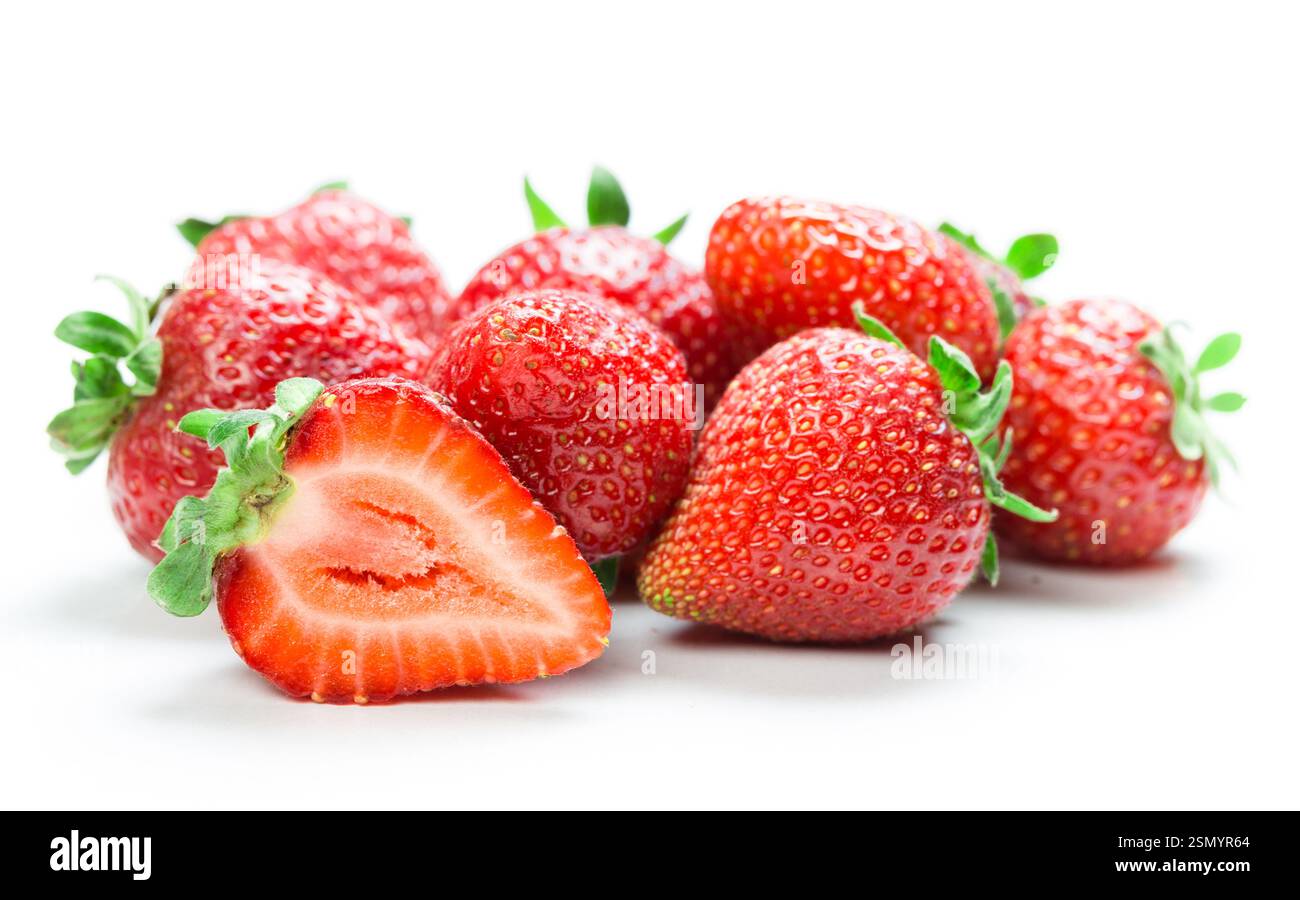 Fragole fresche disposte artisticamente con una tagliata a metà che mostra un interno succoso su sfondo bianco Foto Stock