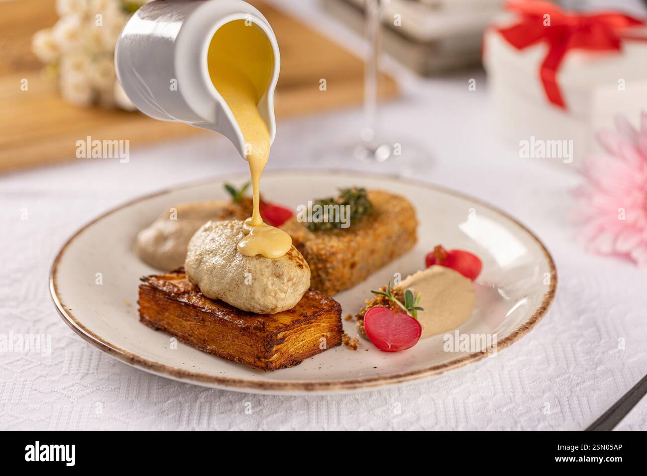 Lo chef versa la salsa sulla polpetta di pollo con patate e guarnisce su un elegante piatto del ristorante Foto Stock
