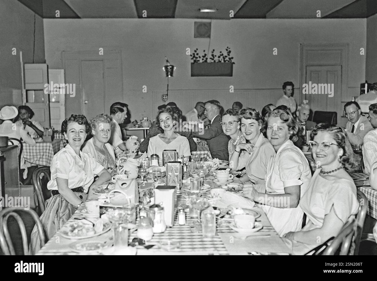 Donne che si godono un pasto fuori insieme negli Stati Uniti c.1960. Il ristorante è piuttosto pieno. Questo è preso dal negativo di un vecchio fotografo amatoriale in bianco e nero - una fotografia vintage anni '1950/'60. Foto Stock