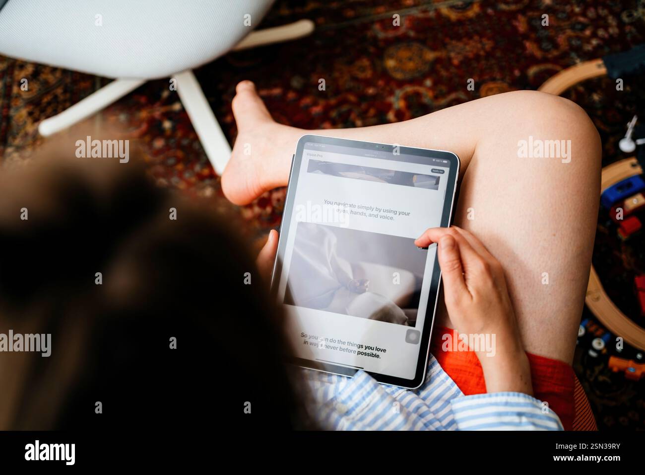 Parigi, Francia - 11 giugno 2023: Una donna seduta comodamente legge su Apple Vision Pro su un tablet, esplorando la sua navigazione a mani libere con gli occhi, ha Foto Stock