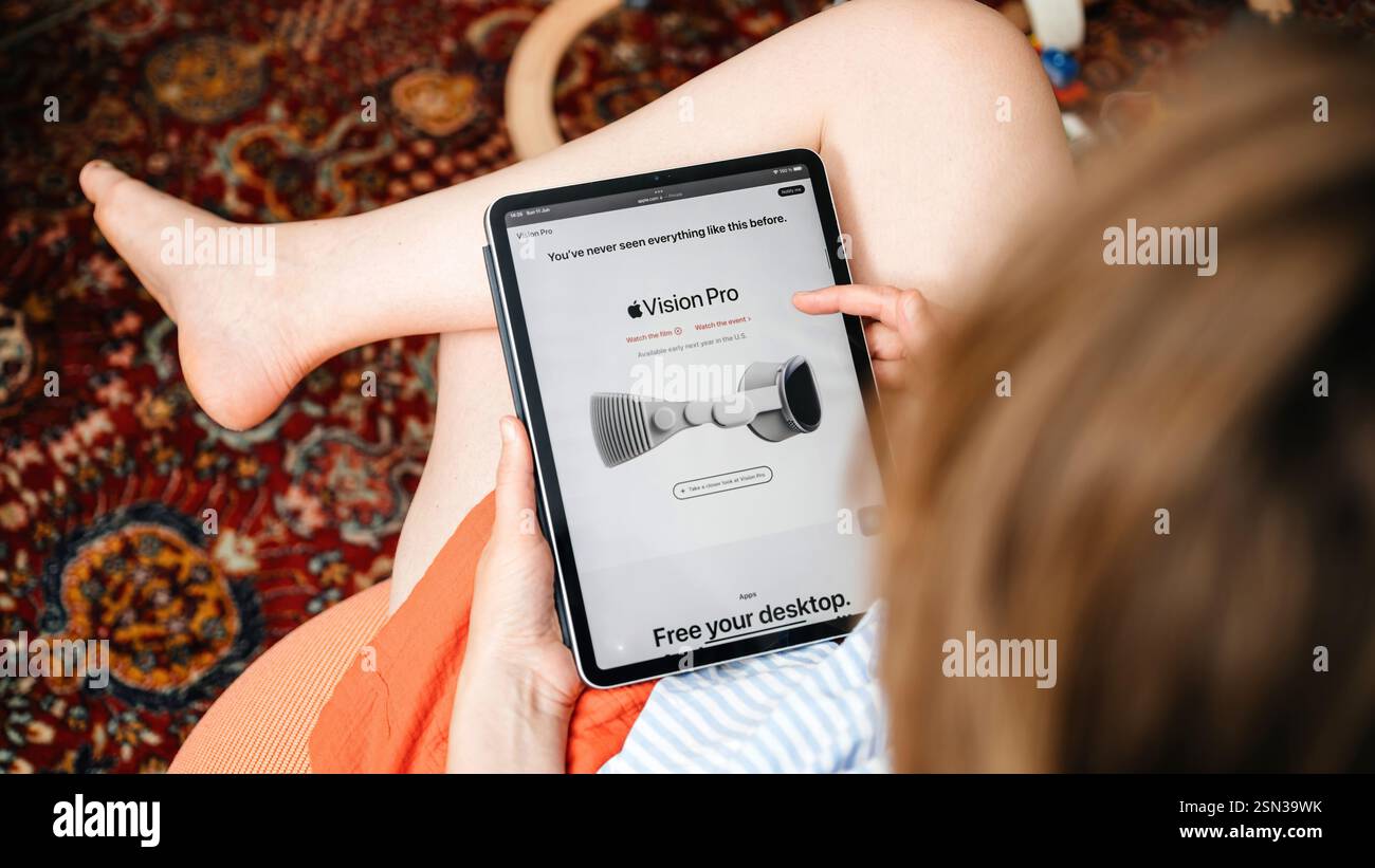 Parigi, Francia - 11 giugno 2023: Una donna siede comodamente, sfogliando un articolo su Apple Vision Pro su un tablet - lo schermo visualizza un'immagine promozionale o Foto Stock