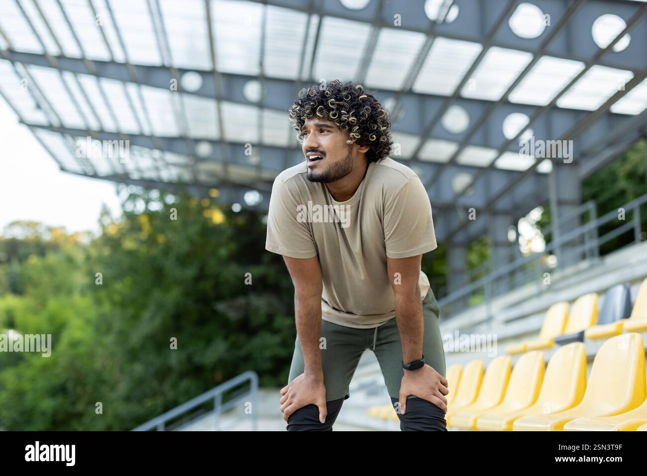 Uomo stanco che riposa e respira profondamente, mancanza di respiro. L'atleta si rilassa dopo l'esercizio fisico attivo e il fitness. Foto Stock