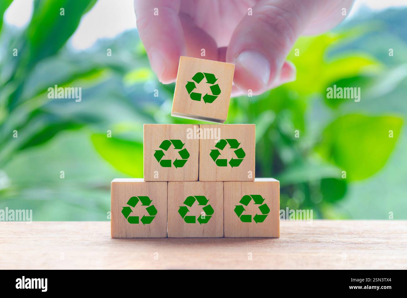 Ricicla i simboli su cubi di legno con sfondo naturale sfocato. Riciclare e preservare il concetto di natura Foto Stock