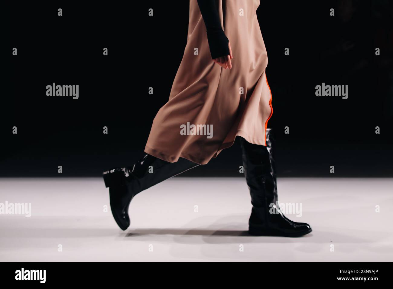 Eleganti dettagli alla moda con gonna marrone setosa e stivali neri, tessuto alla moda da donna su sfondo nero, spazio copia Foto Stock