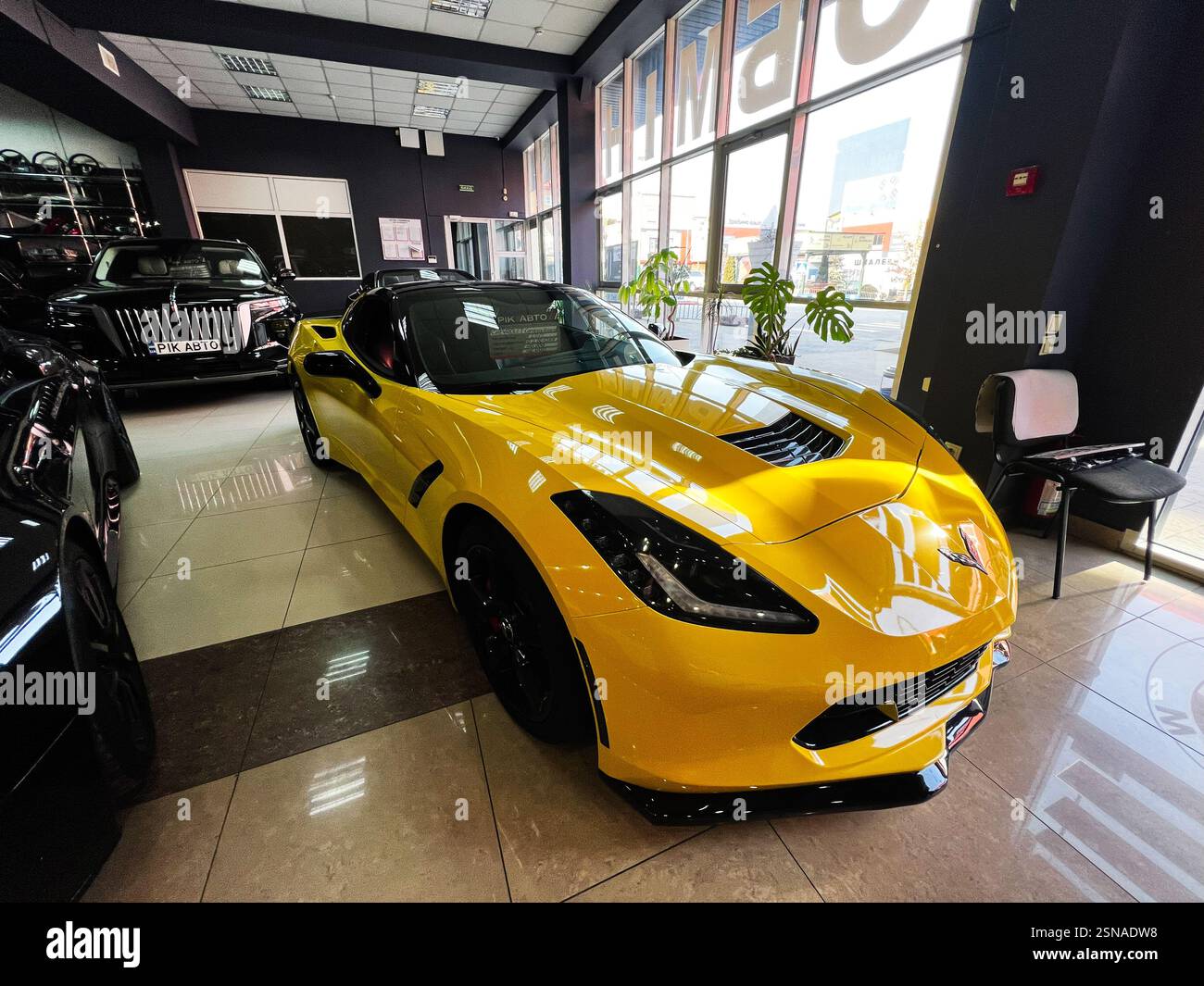 Leopoli, Ucraina - 12 febbraio 2025: Showroom con una Chevrolet Corvette Z06 sportiva di colore giallo brillante e altre automobili di lusso. Foto Stock