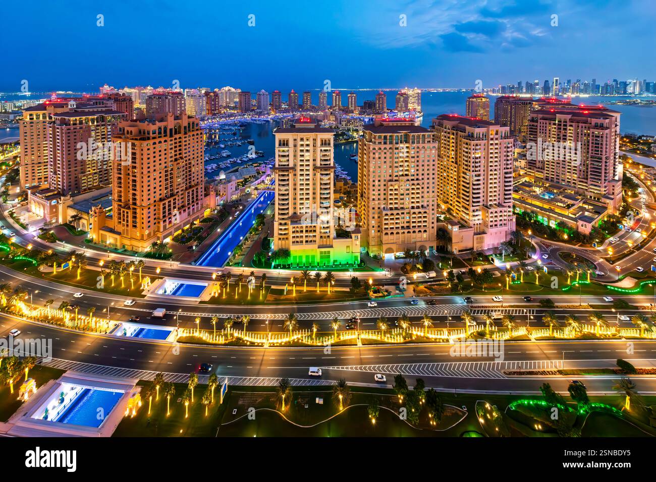 Vista panoramica notturna dall'alto dell'isola illuminata di Doha Pearl con lo skyline della città dietro il Golfo Persico a Doha, Qatar. Foto Stock