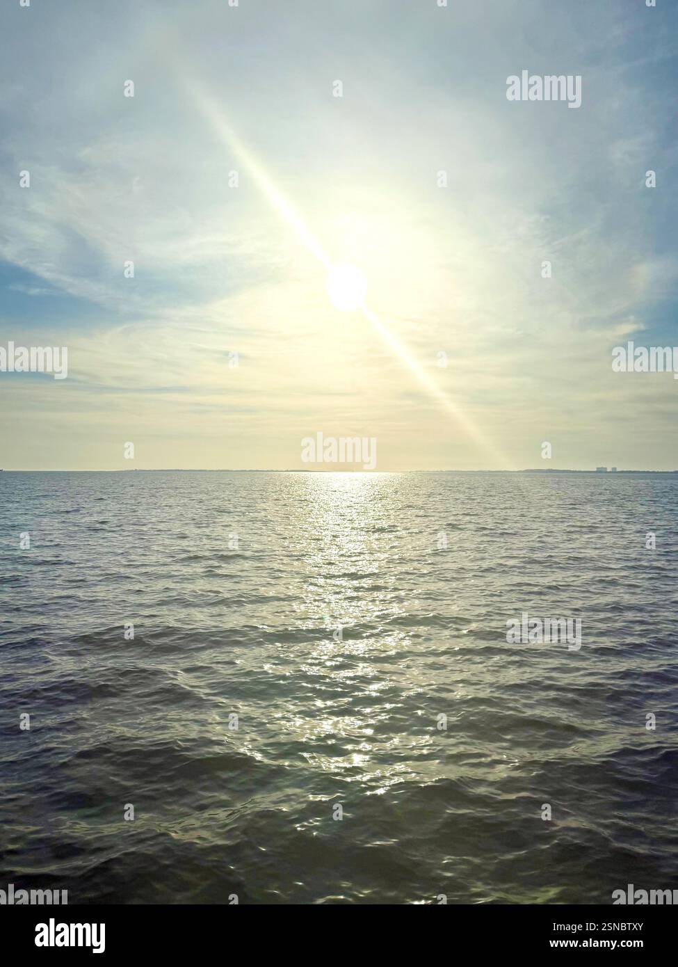Ritratto del sole di mezzogiorno che splende sull'acqua blu brillante Foto Stock