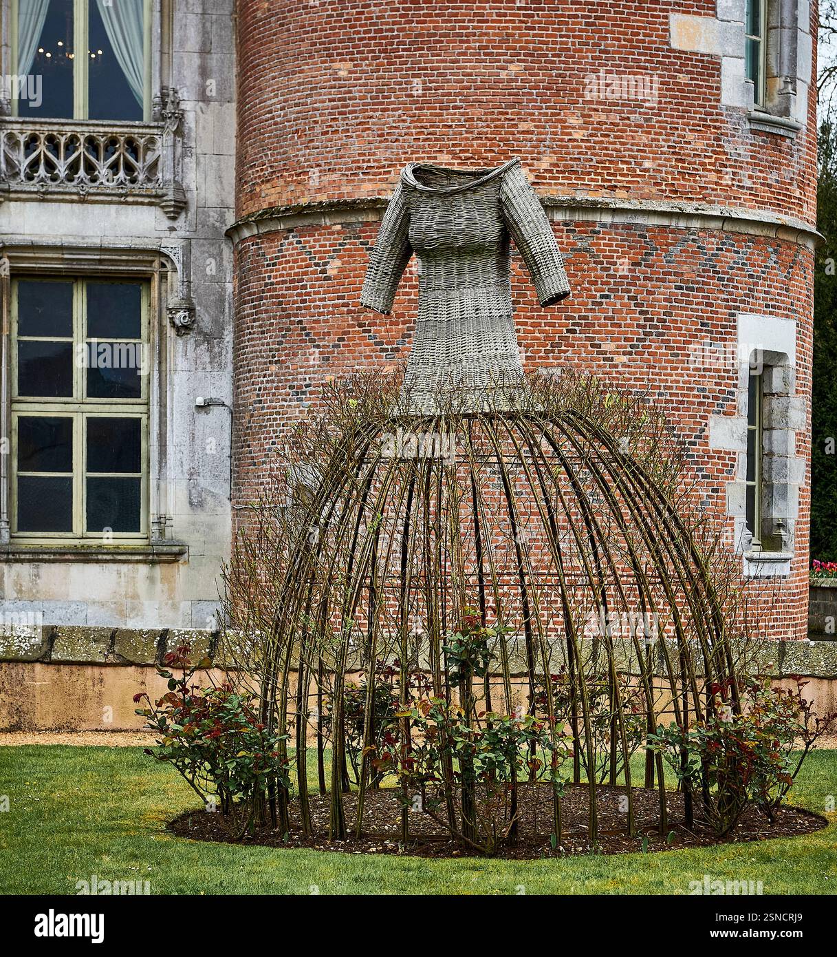 Scultura artistica in vimini di rami di salice intrecciati su un graticcio a cupola davanti alla torre storica del castello in mattoni dello Château de Maintenon, Francia Foto Stock