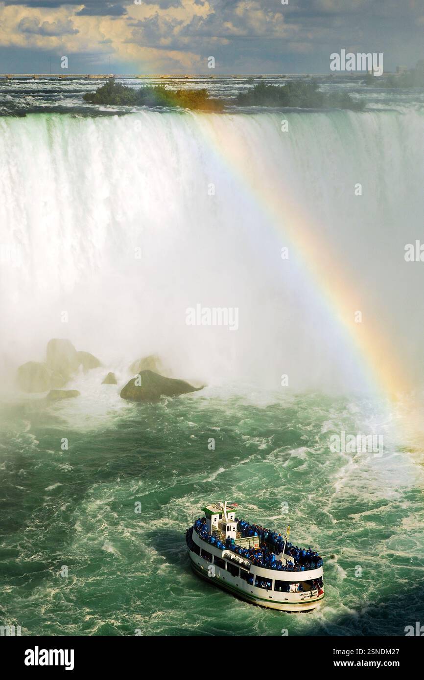 Il tour in barca Maid of the Mist si ferma vicino alle cascate canadesi mentre un arcobaleno si sviluppa nella nebbia Foto Stock