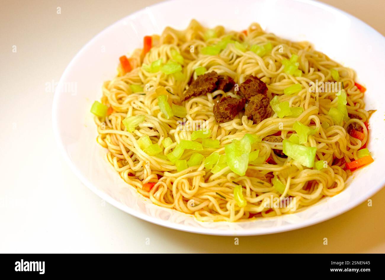 Spaghetti fritti in stile asiatico con cavolo, manzo e verdure, serviti su un piatto bianco. Pasto tradizionale fatto in casa Foto Stock