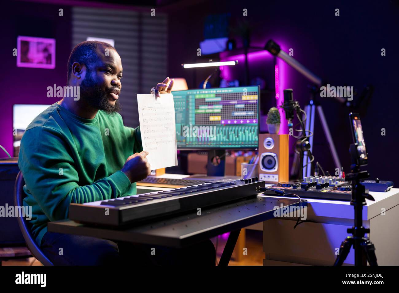 Artista che punta alla notazione del foglio musicale per spiegare le note al pianoforte, insegnando alle persone a suonare il sintetizzatore in casa studio. Famoso compositore musicista che suona il controller Midi durante la master class online. Foto Stock