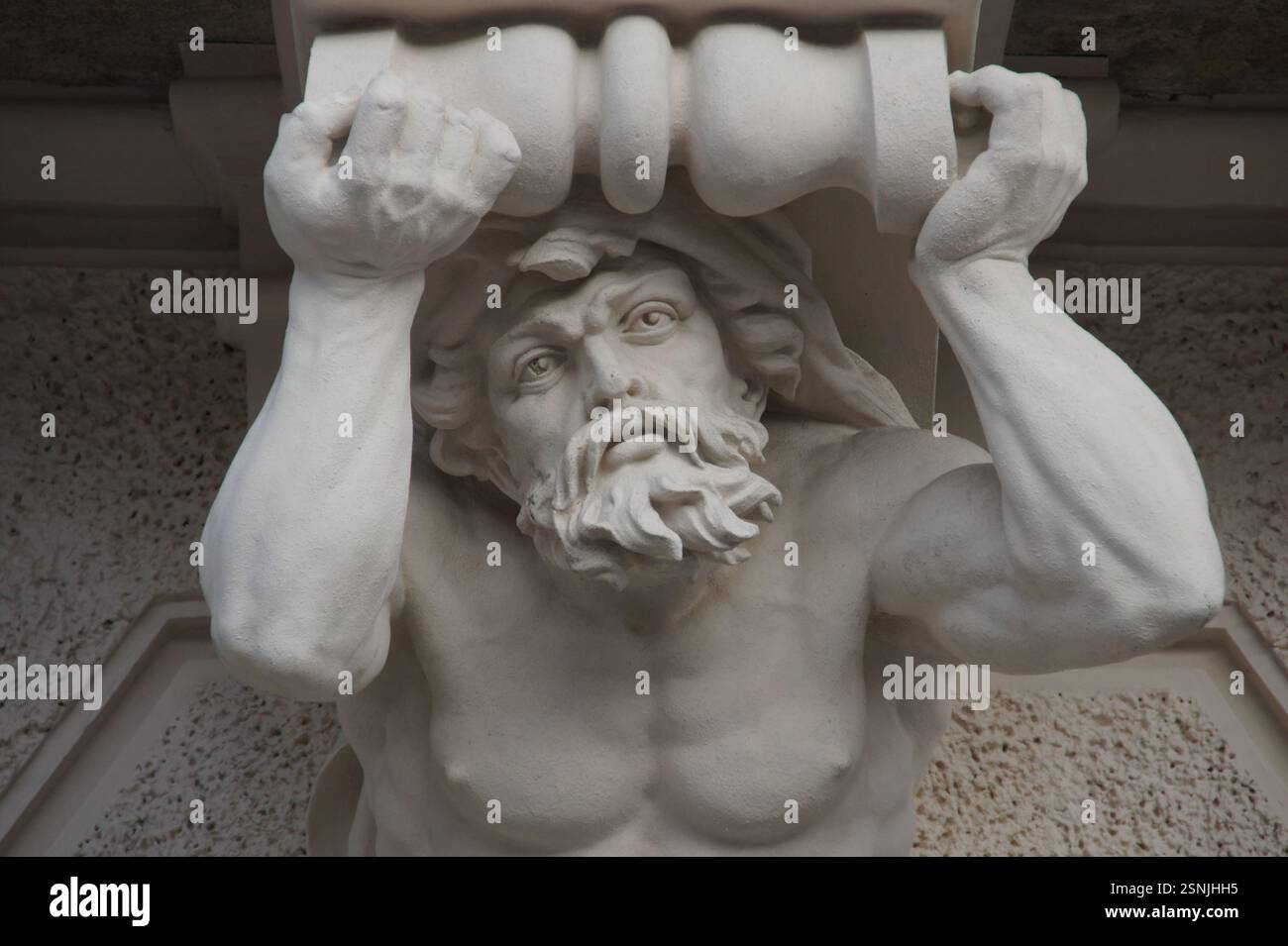 In Germania, Monaco di Baviera, una scultura insolita raffigura un uomo barbuto appeso a testa in giù da un edificio. Rivestita di abbigliamento contemporaneo, la figura in bronzo S Foto Stock