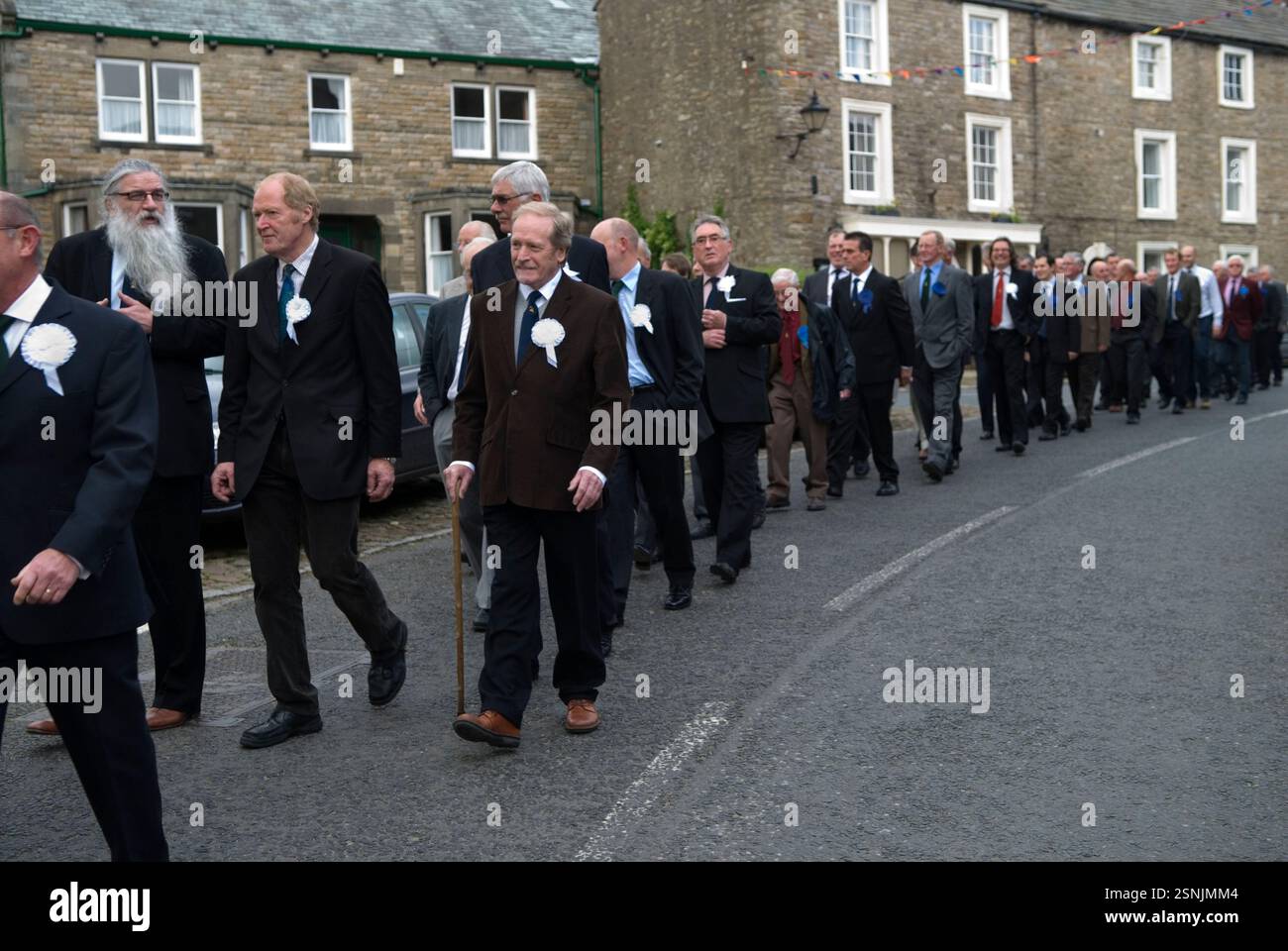 Friendly Societies UK. L'Askrigg Friendly Society, la loro parata annuale lascia il Kings Arms Hotel per la chiesa di St Oswalds, dove si svolge un breve servizio. I membri onorari indossano rosoni bianchi, mentre quelli ordinari indossano una blu. Askrigg, North Yorkshire, Inghilterra 5 giugno 2014 2010s UK HOMER SYKES Foto Stock