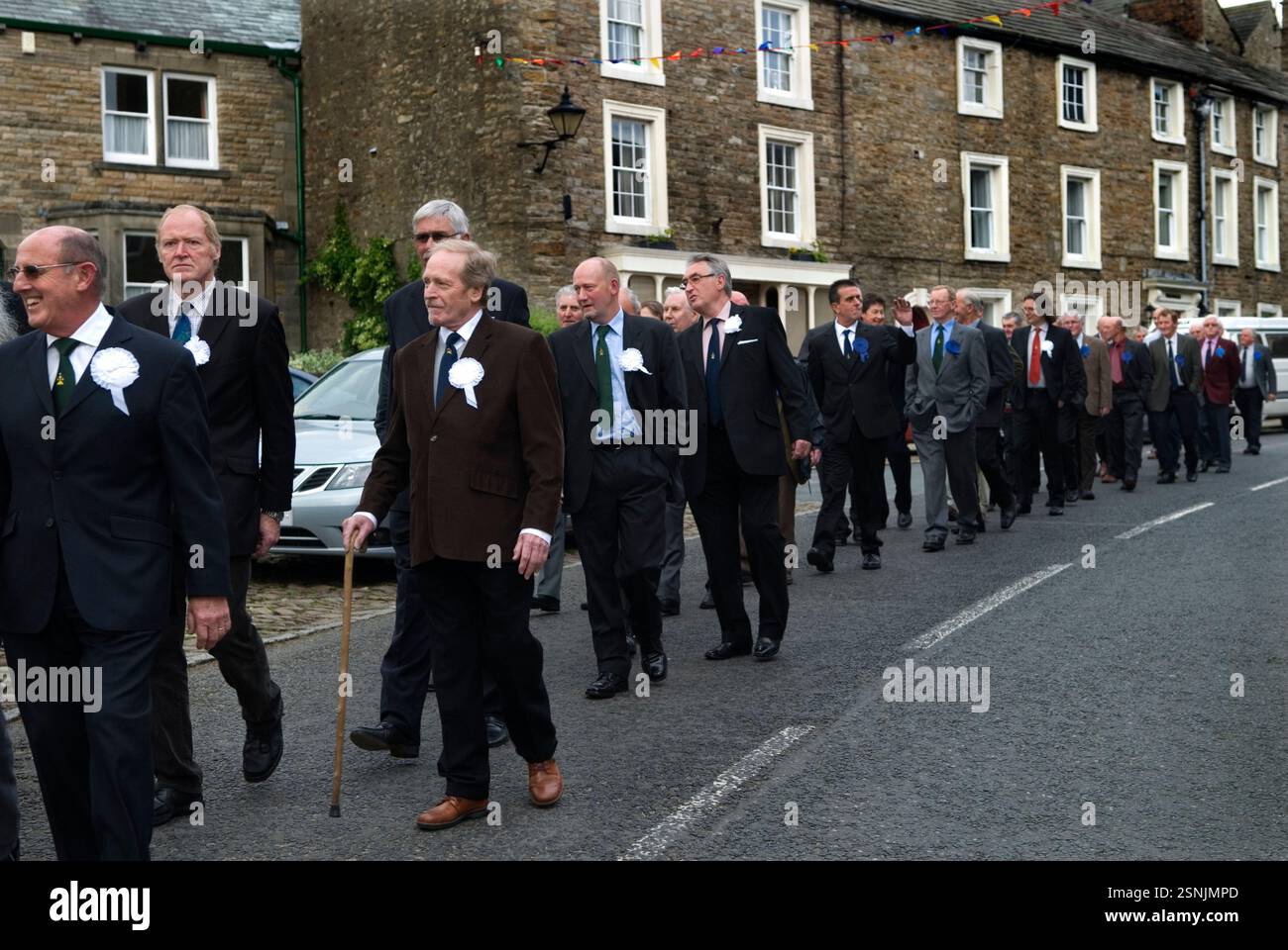 Askrigg Friendly Society. La parata annuale lascia il Kings Arms Hotel per la chiesa di St Oswalds, dove si svolge un breve servizio. I membri onorari indossano rosoni bianchi, mentre quelli ordinari indossano una blu. Askrigg, North Yorkshire, Inghilterra 5 giugno 2014 2010s UK HOMER SYKES Foto Stock