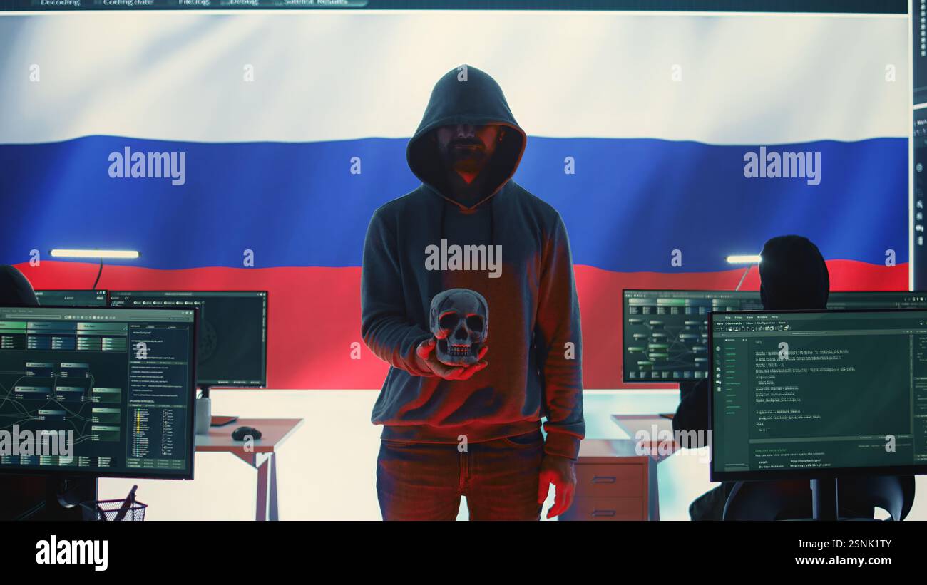 Hacker digitale fuorilegge in un buio buio che emette minacce informatiche con un cranio umano per rendere minacce di morte, intento aggressivo e dannoso. Uomo russo che commette crimini informatici e truffa le nazioni. Telecamera B.. Foto Stock
