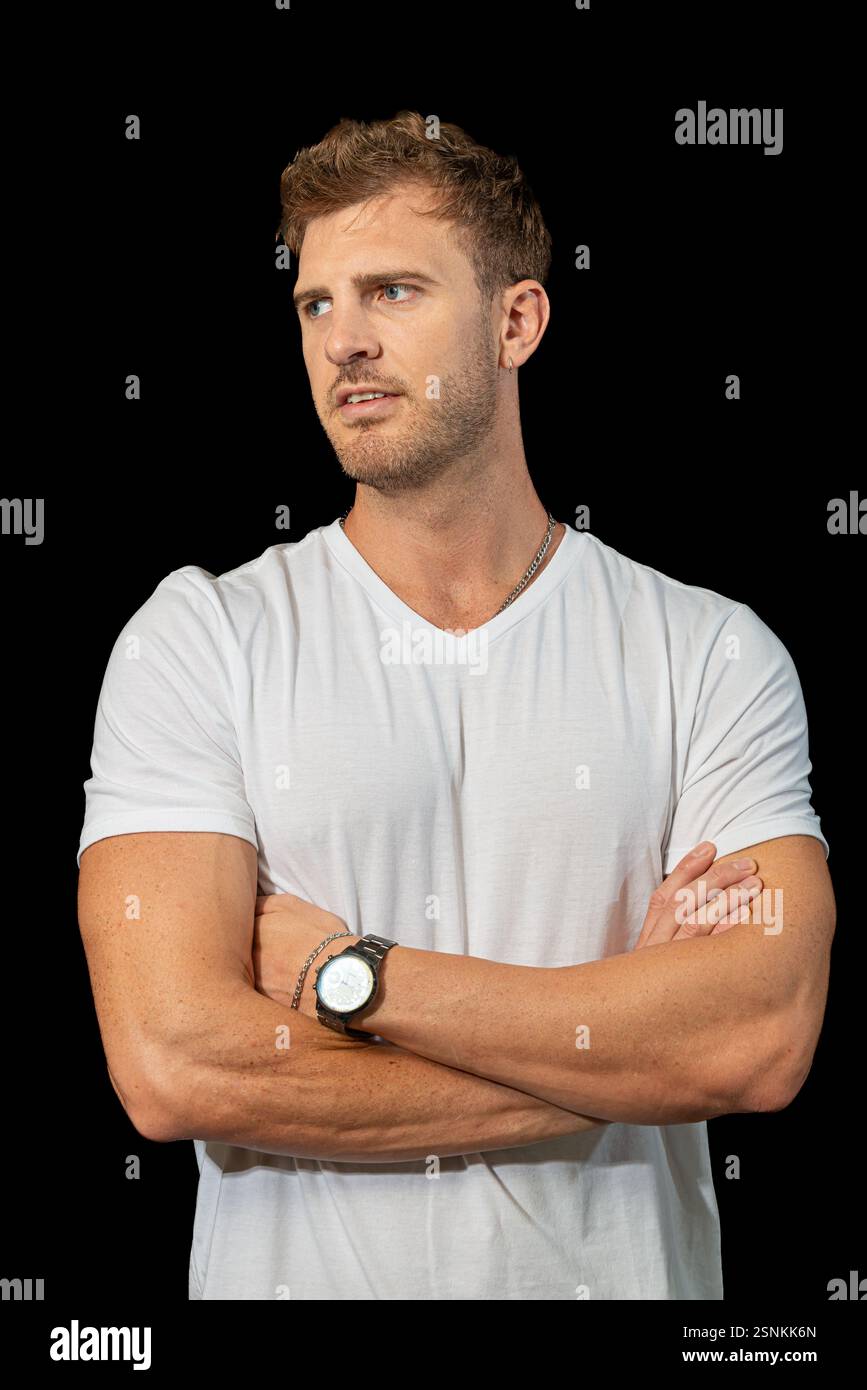Un uomo biondo elegante indossa con sicurezza una classica t-shirt bianca e jeans blu, incarnando la moda disinvolta e lo stile casual moderno Foto Stock
