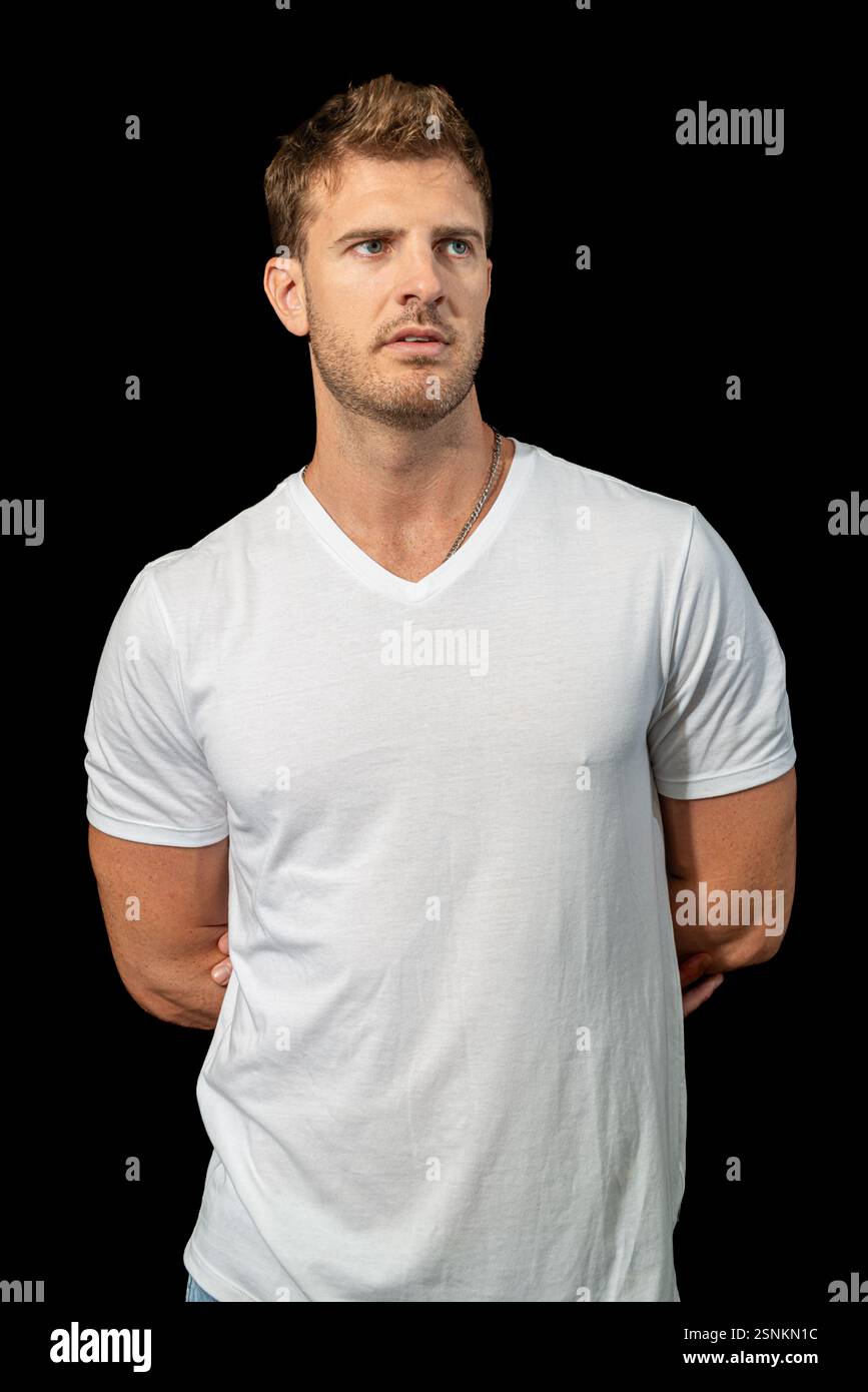 Un uomo biondo elegante indossa con sicurezza una classica t-shirt bianca e jeans blu, incarnando la moda disinvolta e lo stile casual moderno Foto Stock