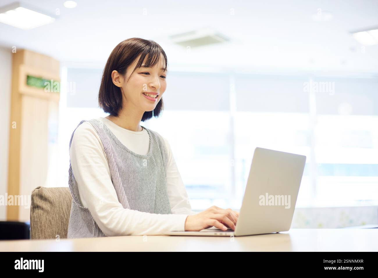 Lavoratrice di assistenza all'infanzia al lavoro che utilizza un computer portatile presso un centro di assistenza diurna Foto Stock