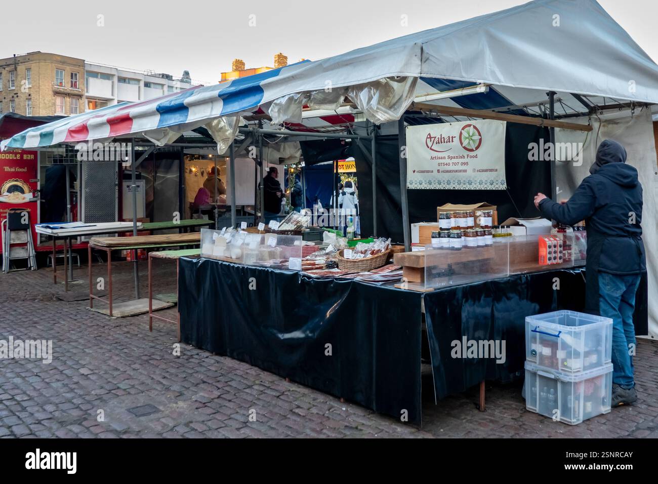 Il mercato all'aperto offre piatti e prelibatezze artigianali spagnoli, mostrando venditori locali in un vivace ambiente urbano nel mercato di Cambridge. Foto Stock