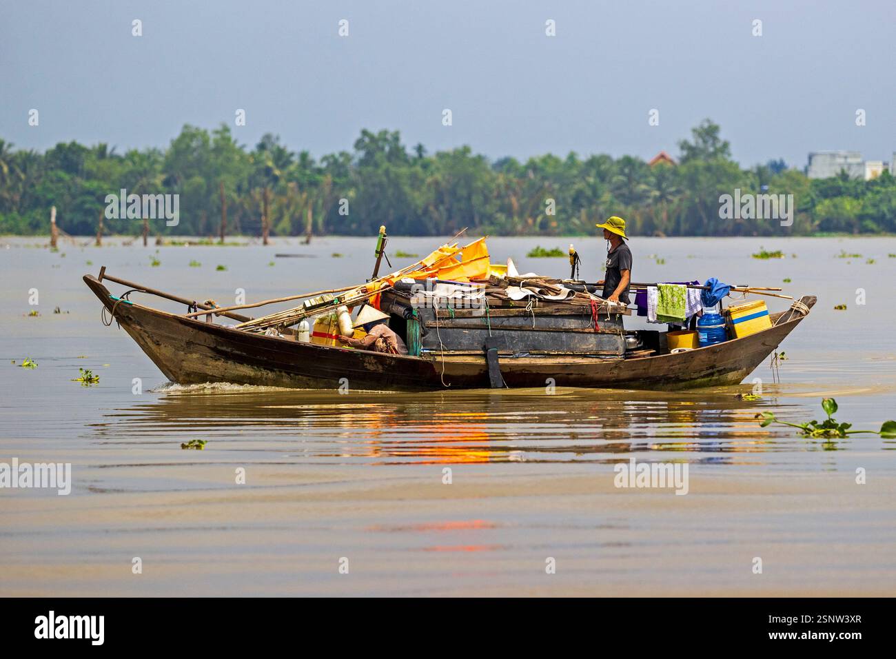 Fisherman naviga sul fiume Mekong su una barca di legno durante il giorno con rifornimenti e strumenti per il lavoro in Vietnam, lunedì 11 novembre 2024. Foto Stock