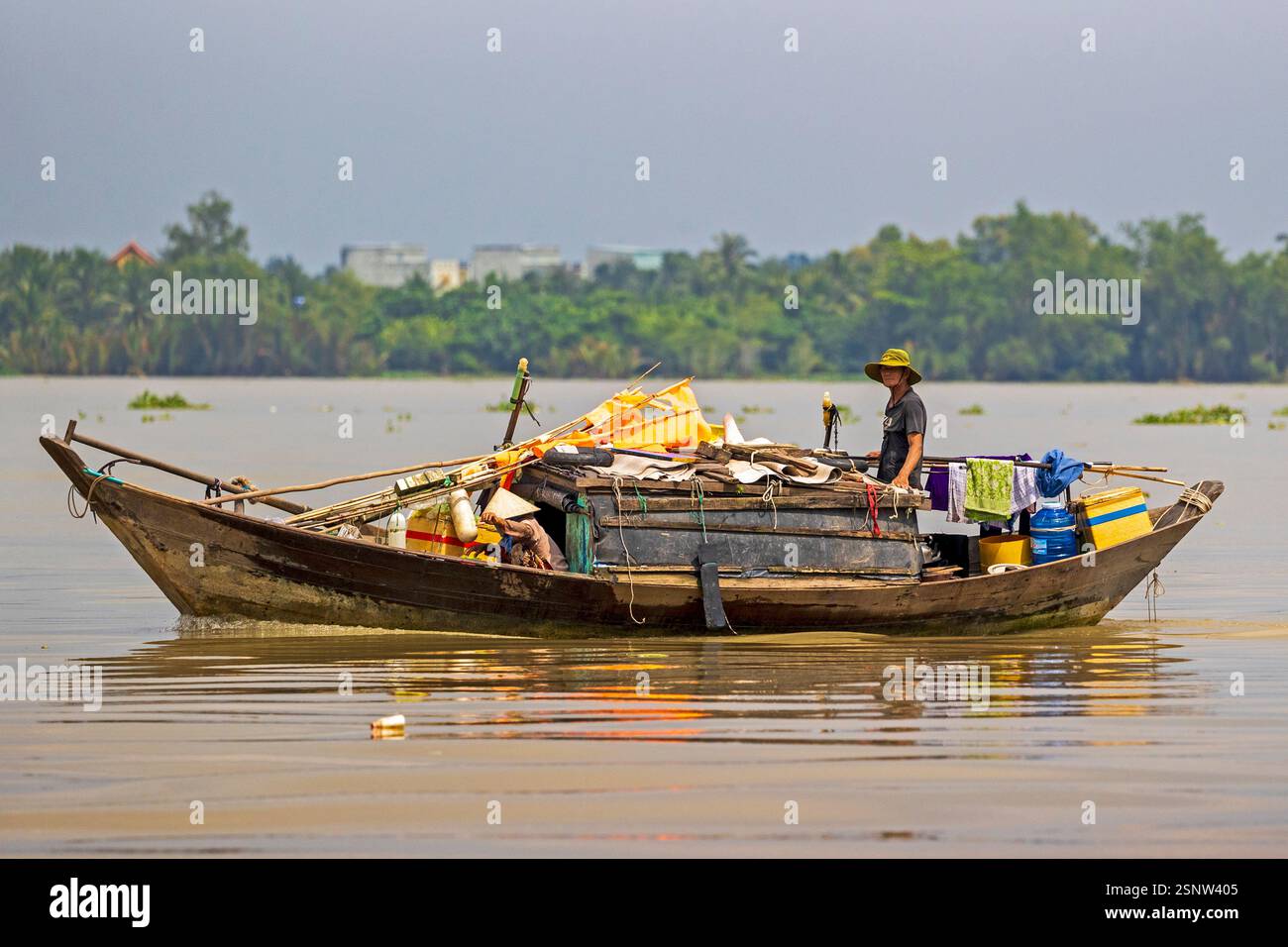 Fisherman naviga sul fiume Mekong su una barca di legno durante il giorno con rifornimenti e strumenti per il lavoro in Vietnam, lunedì 11 novembre 2024. Foto Stock