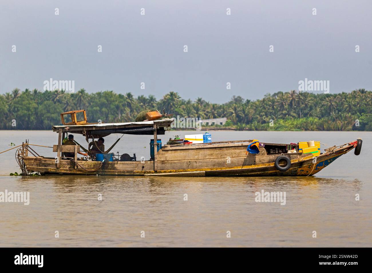 Fisherman naviga sul fiume Mekong su una barca di legno durante il giorno con rifornimenti e strumenti per il lavoro in Vietnam, lunedì 11 novembre 2024. Foto Stock