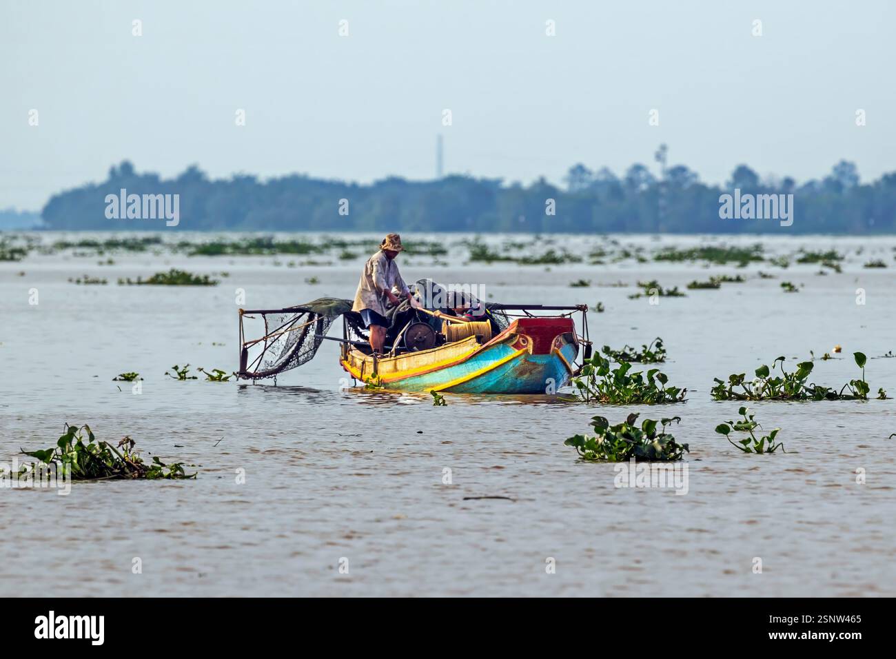 Fisherman naviga sul fiume Mekong su una barca di legno durante il giorno con rifornimenti e strumenti per il lavoro in Vietnam, lunedì 11 novembre 2024. Foto Stock