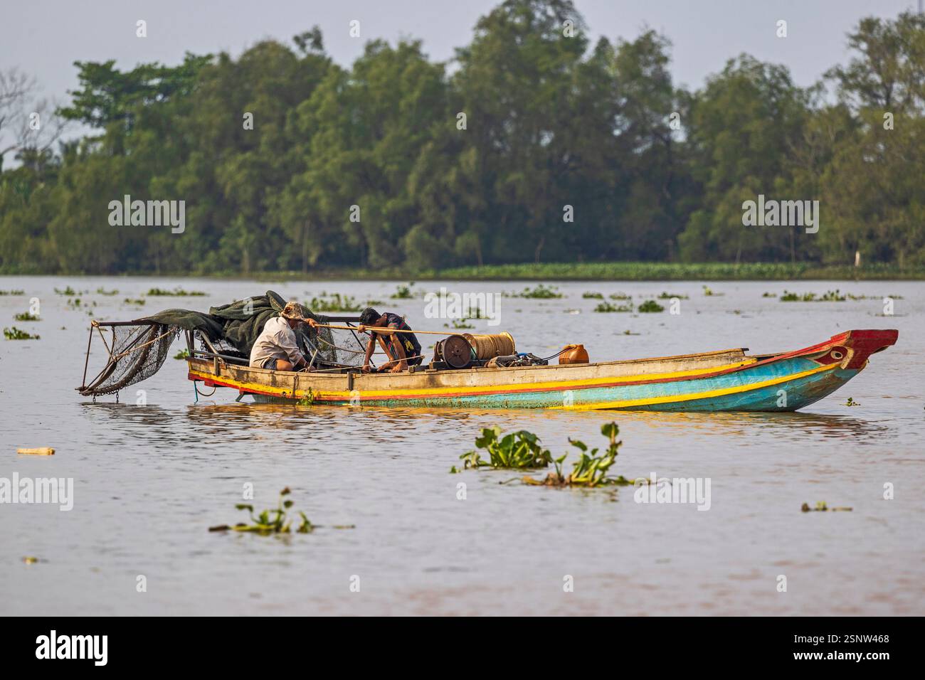 Fisherman naviga sul fiume Mekong su una barca di legno durante il giorno con rifornimenti e strumenti per il lavoro in Vietnam, lunedì 11 novembre 2024. Foto Stock