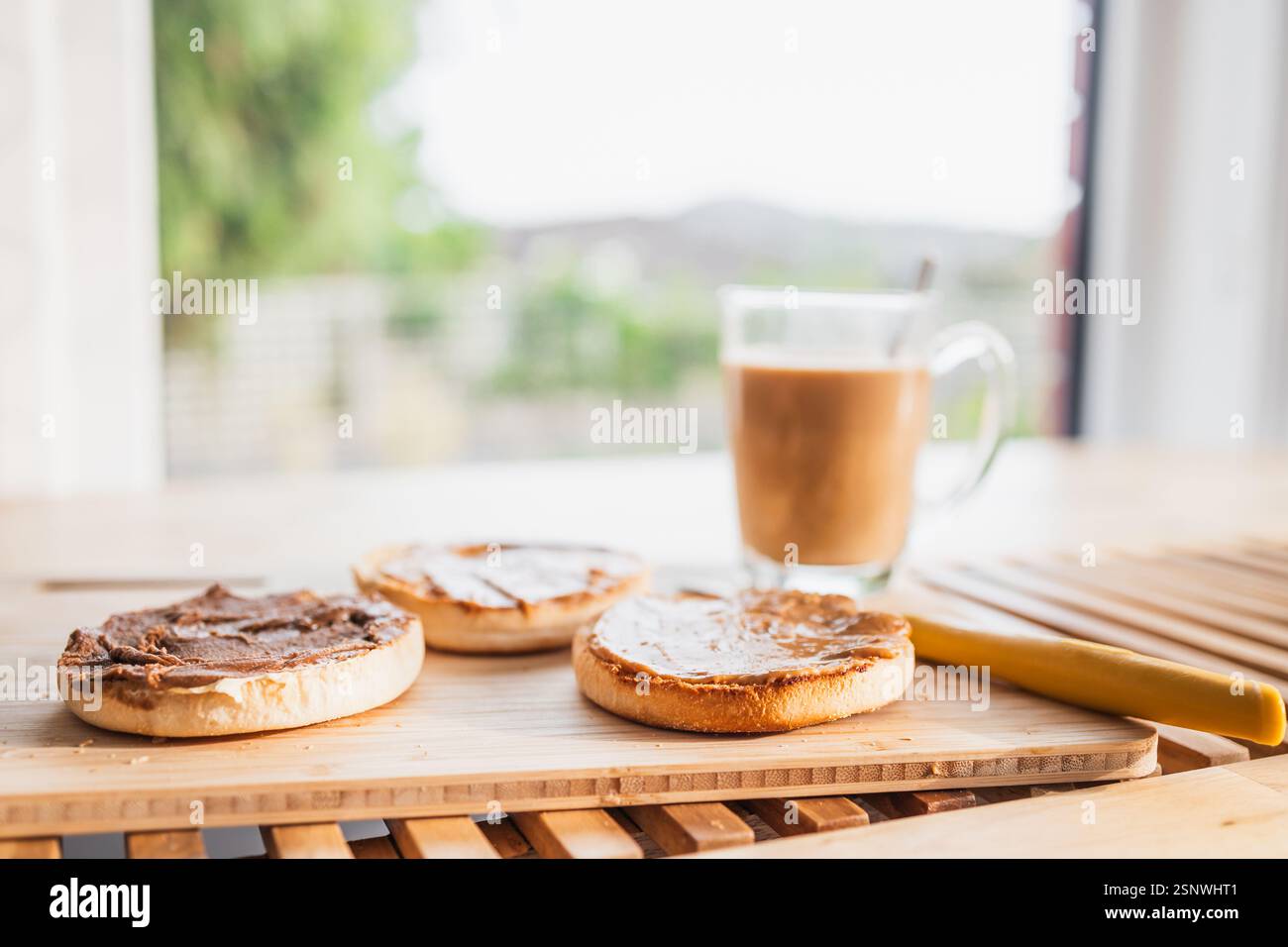 Muffin inglesi al burro di arachidi e cioccolato con tazza da caffè sul tavolo della colazione con bokeh sul cortile, concetto di semplice routine quotidiana Foto Stock Muffin inglesi al burro di arachidi e cioccolato con tazza da caffè sul tavolo della colazione con bokeh sul cortile, concetto di semplice routine quotidiana Foto Stock