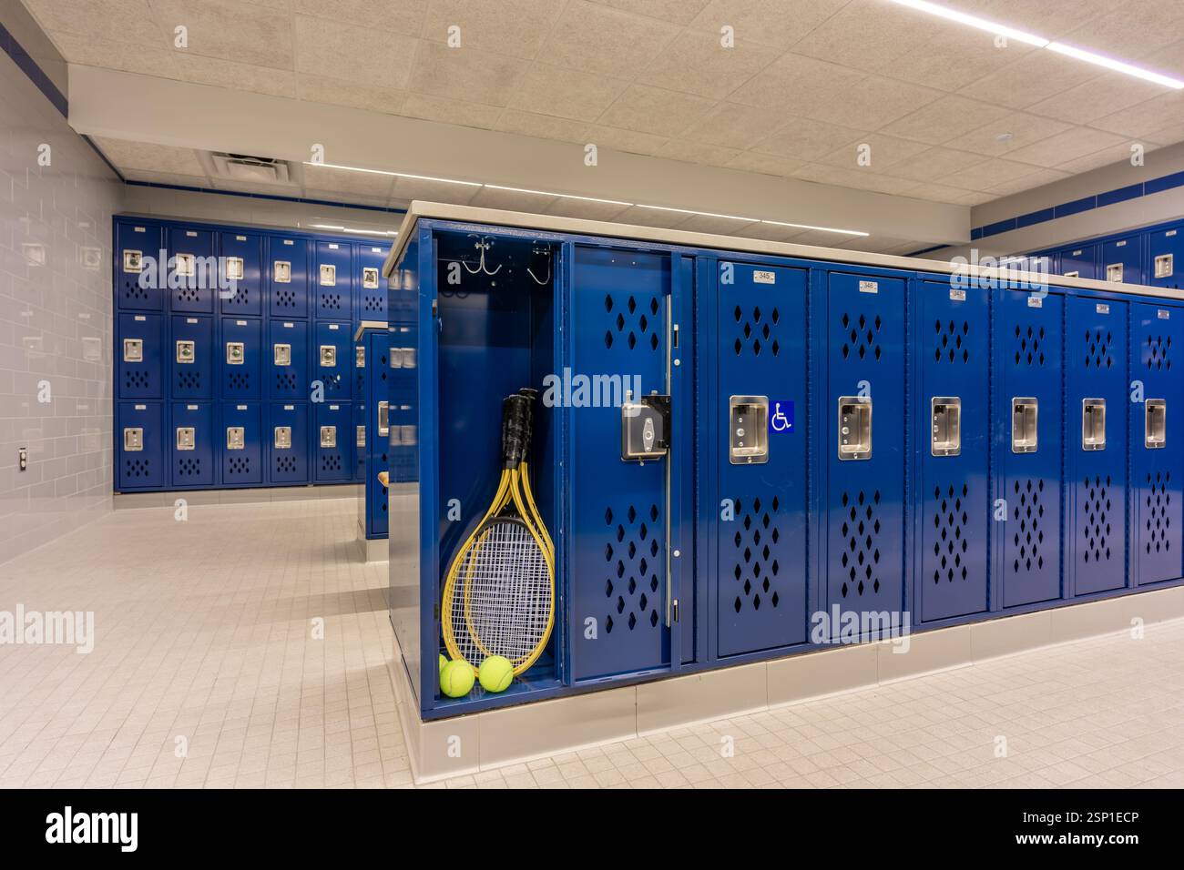 Armadietto per squadre vuoto, spogliatoio, spogliatoio, con un armadietto aperto contenente palle da tennis con racchette da tennis e tradizionali armadietti blu in metallo. Foto Stock
