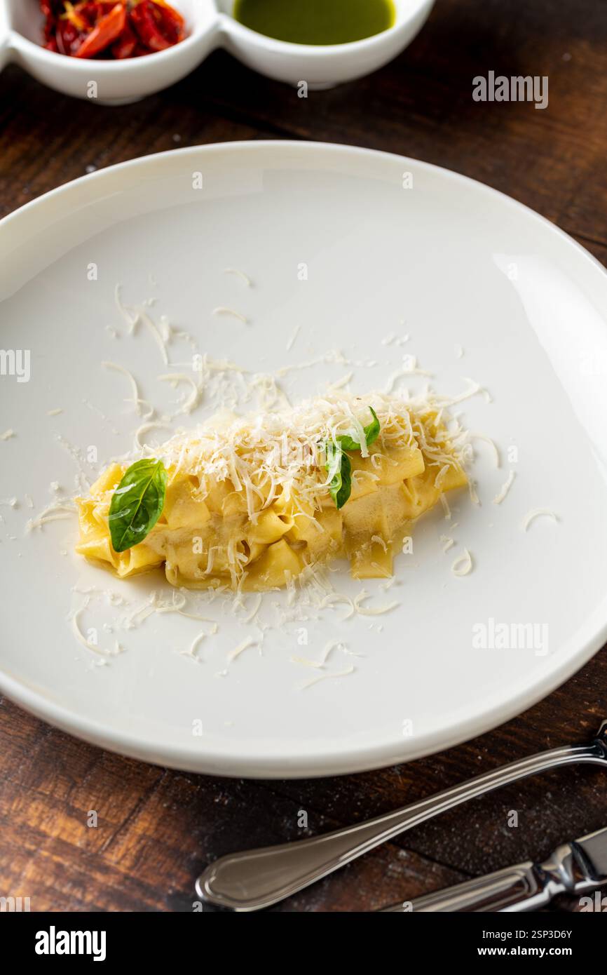 Deliziosa pappardelle di pasta italiana con parmigiano in porcellana bianca su un tavolo di legno Foto Stock